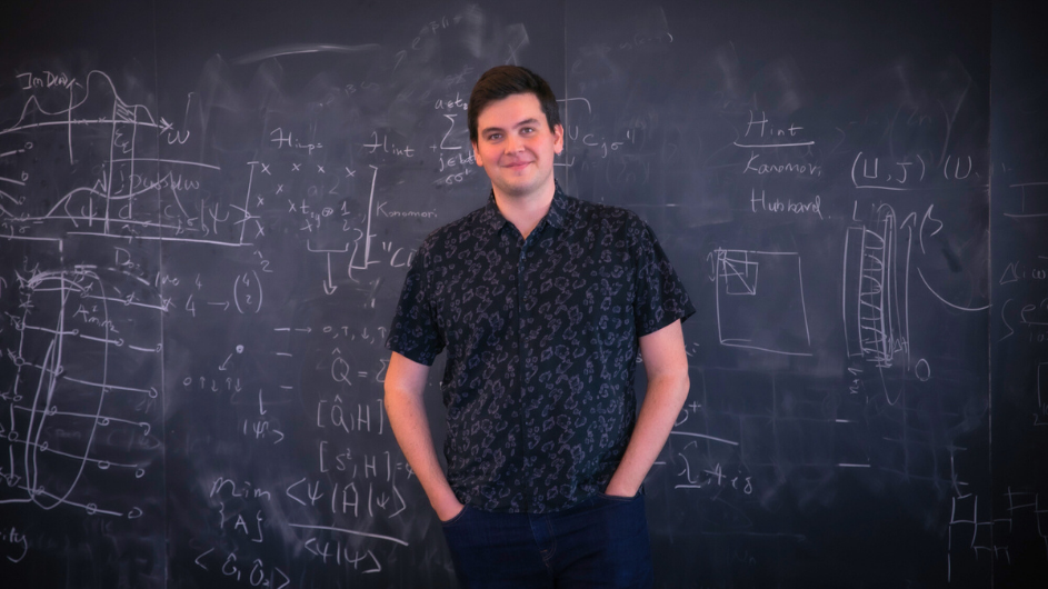 Matija in front of a blackboard with quantum mechanics equations. 