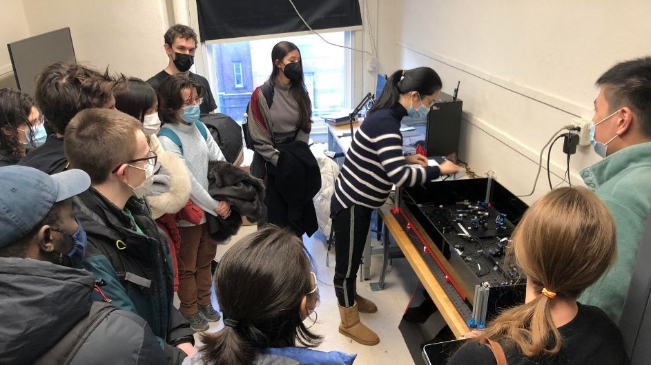 Teaching Assistant Shuhan Zhang explains QuTools, hardware for entangling photons for quantum computing, to the class Shuhan Zhang and Columbia students in front of the QuTools hardware