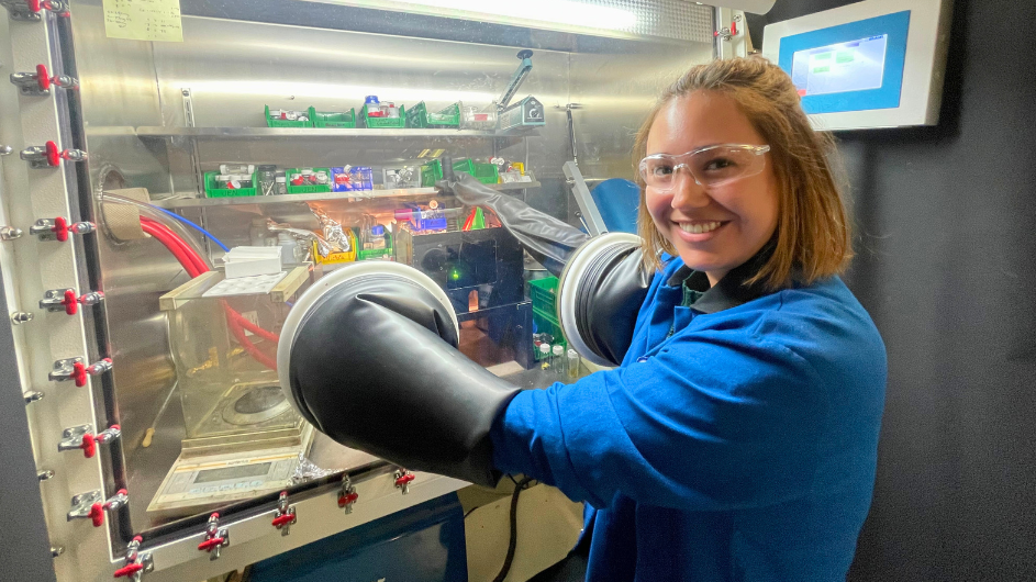 Victoria Posey with her hands in the glove at a glovebox in the lab of Columbia chemist Xavier Roy.