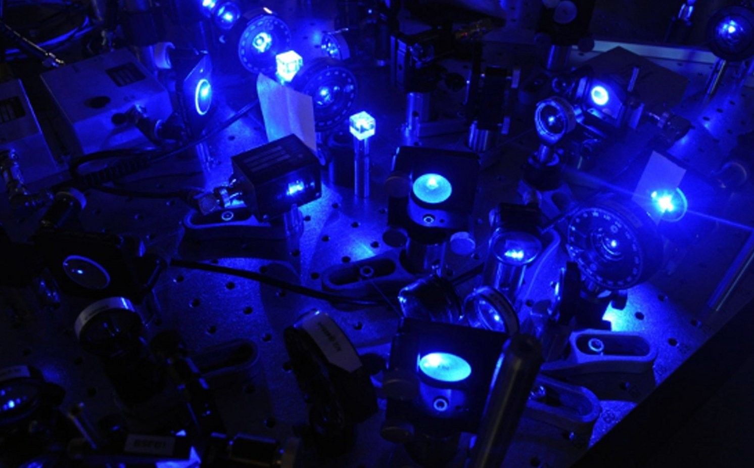 Lab table with a series of blue lasers. 