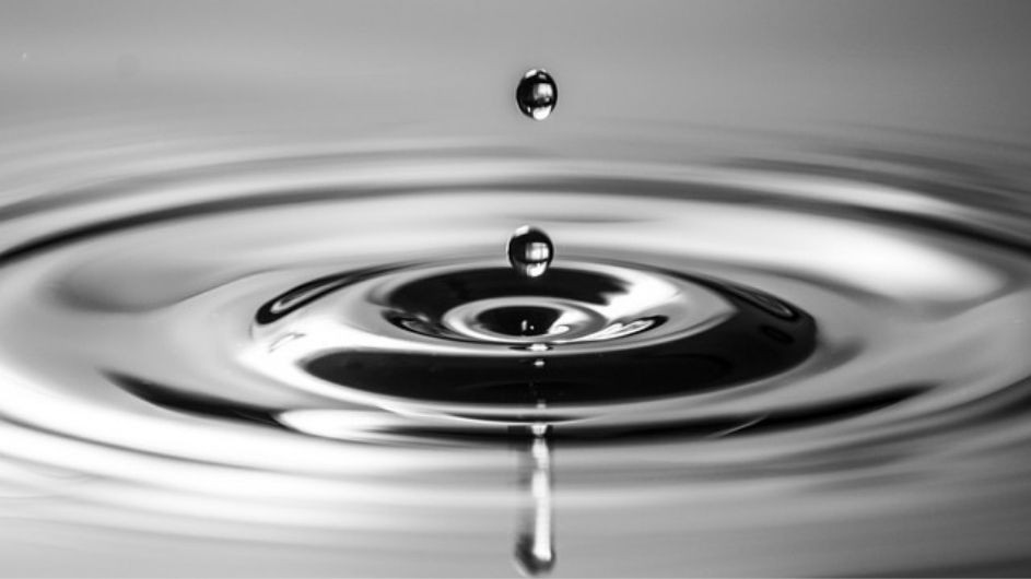 Black and white photo of droplets rippling in water, representing many-body localization