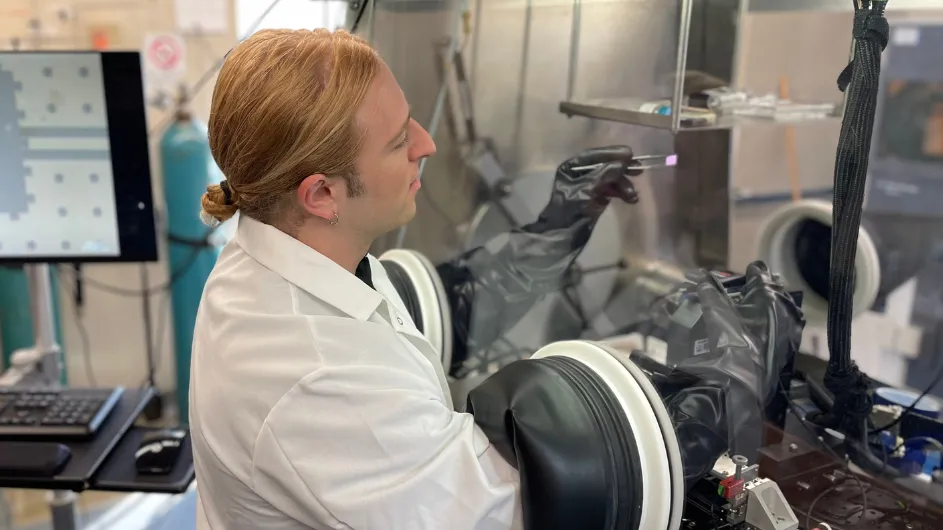 Jesse Balgley holding a chip inside an air-free glovebox