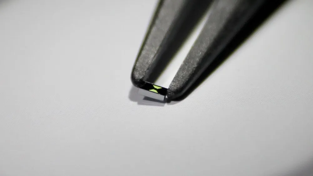 Tweezers holding a tiny photonic chip from the Gaeta Lab 